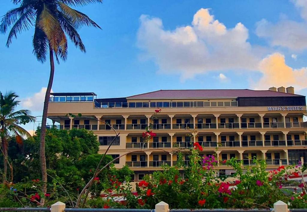 a hotel with a palm tree and a building at Myah's Hotel in Brighton Village