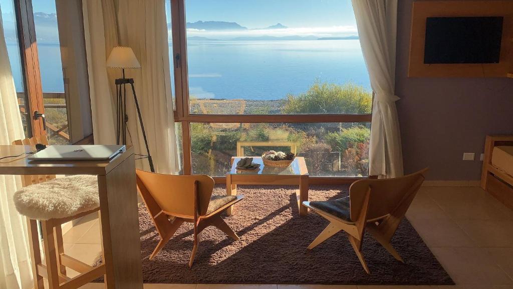 uma sala de estar com uma mesa e cadeiras e uma grande janela em Blue Aparts Dina Huapi Bariloche em Dina Huapi