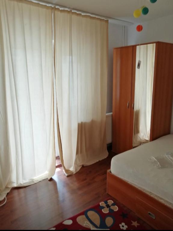- une chambre avec des rideaux blancs, un lit et une armoire dans l'établissement Apartament Ploiesti, à Ploieşti