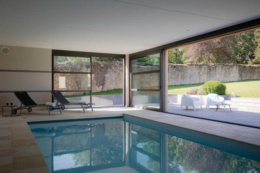 una piscina en una casa con ventanas de cristal en Domaine La Buissonnière 