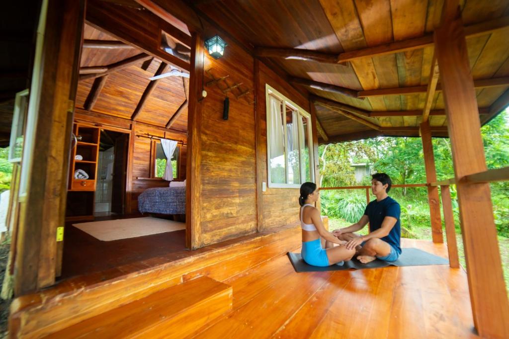 a man and a woman sitting on the floor of a house at Galapagos Cabañas Eden in Bellavista