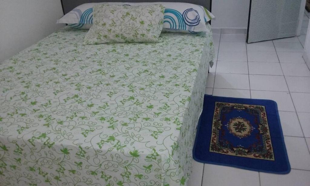 a bed with a green and white comforter and pillows at Apartamento Pelourinho in Salvador