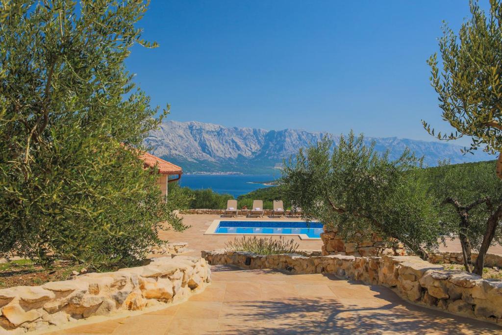 a house with a swimming pool and a lake at Ferienhaus Luisa Insel Brac - Kamin, Pool, Grill, Olivengrundstück in Pučišća