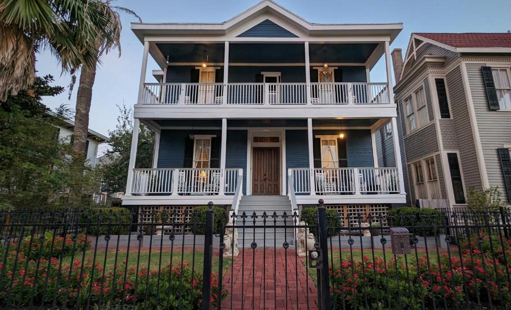 a blue house with a balcony and a gate at The 1890 Freeman House in Galveston