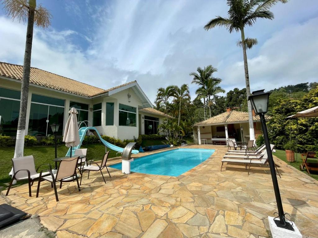 a swimming pool with chairs and a slide next to a house at Casa de campo, com quadra de Beach Tennis, Volei e Fut Volei próxima a SP!! in Santana de Parnaíba