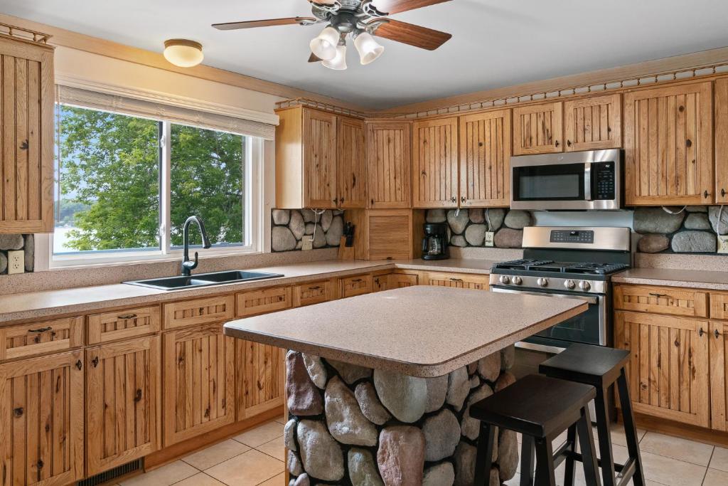 una cocina con armarios de madera y una isla de piedra en Fife Lake Lodge 2BR with Kitchen & Lake Views en Fife Lake