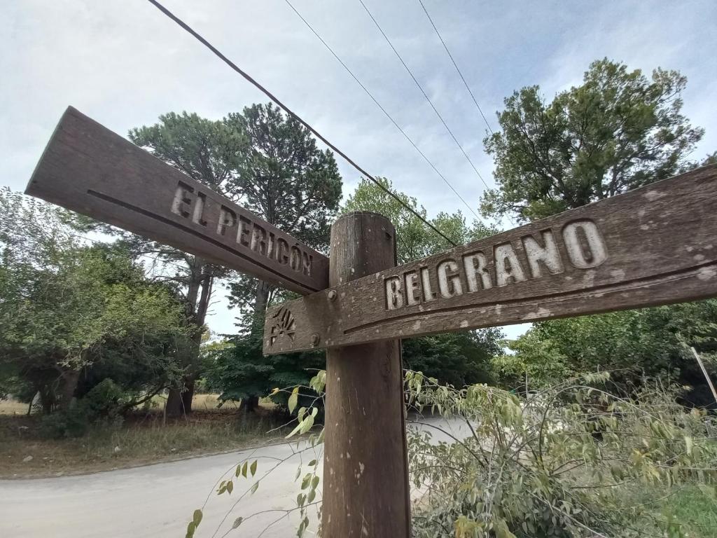 a wooden street sign with the names of two streets at El Pericon y Belgrano in Punta Indio