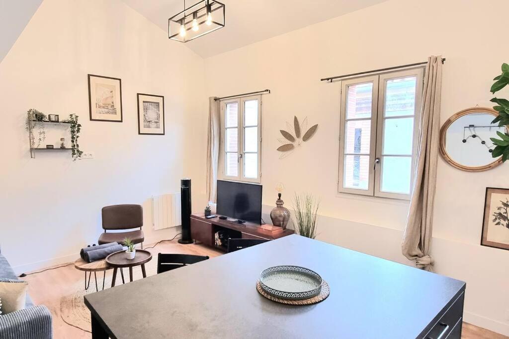 een woonkamer met een tafel en een televisie bij Le Duplex Catherine - Metro - Gare - WIFI in Toulouse