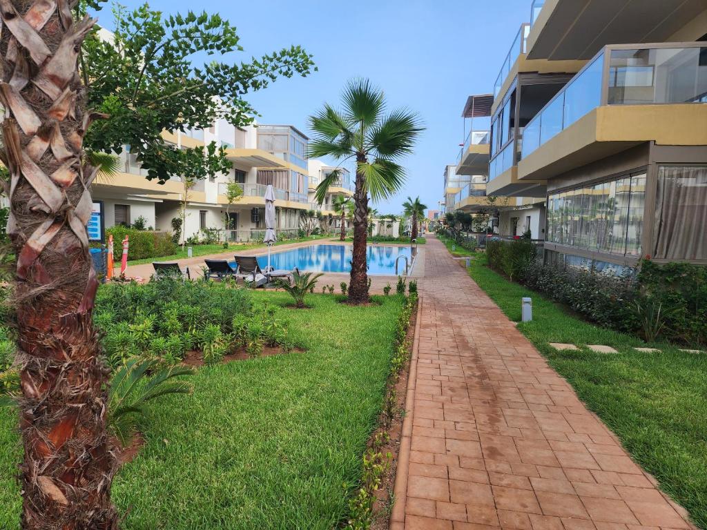 a walkway next to a resort with a swimming pool at Blue Beach Sidi rahal in Sidi Rahal