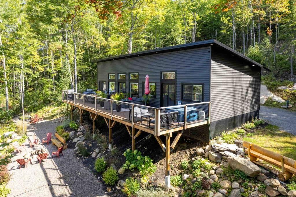 ein schwarzes winziges Haus mit einer Terrasse im Wald in der Unterkunft Maple Ridge Cottage 