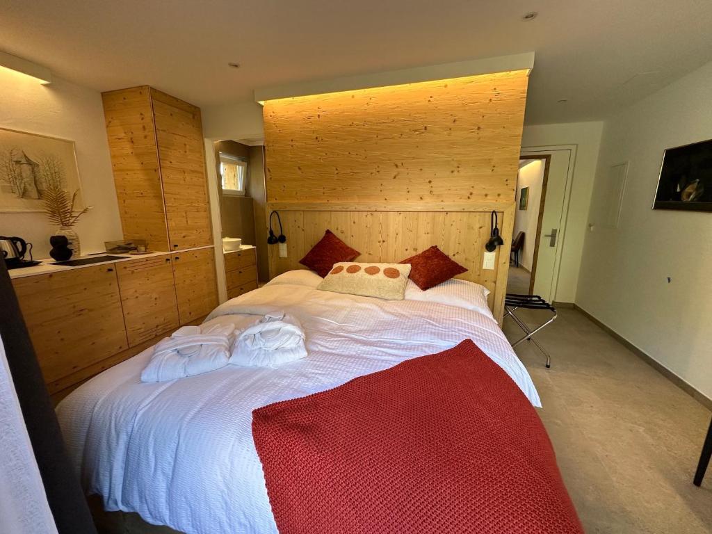 sypialnia z dużym białym łóżkiem z drewnianym zagłówkiem w obiekcie John's Lodge w mieście Les Collons