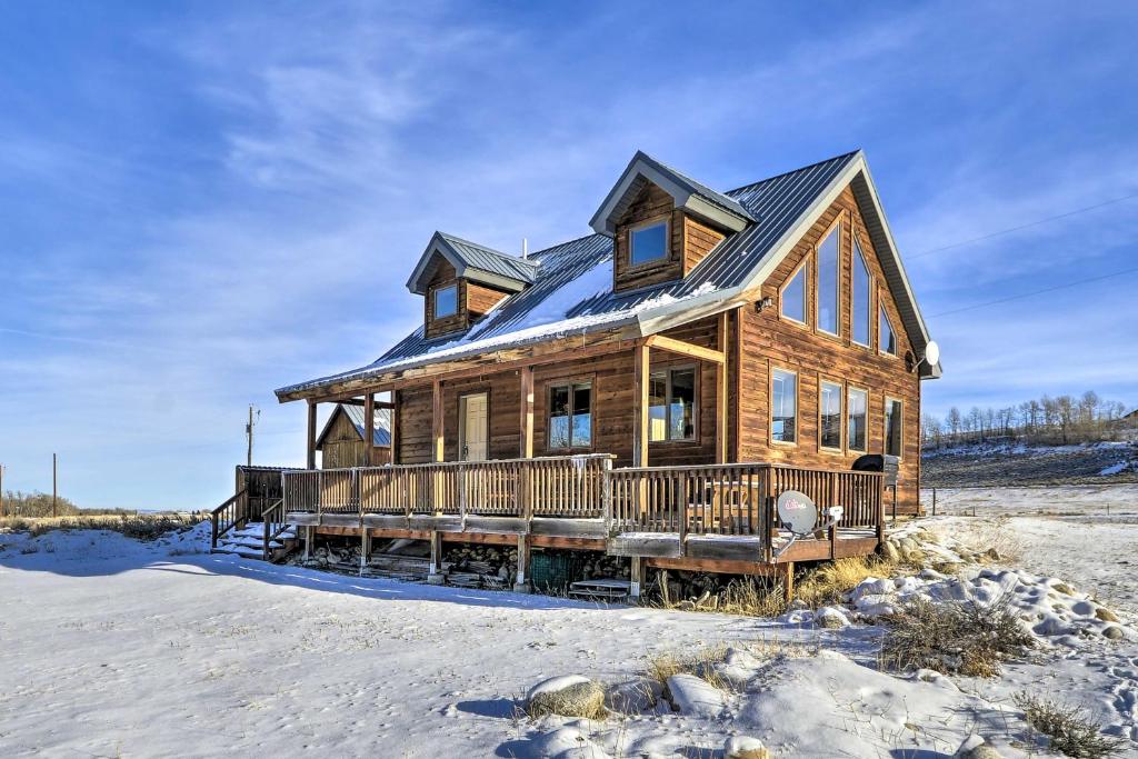 una casa de madera con techo de gambrel en la nieve en Off The Beaten Path Cabin with Mtn Views and Hot Tub en Red Lodge