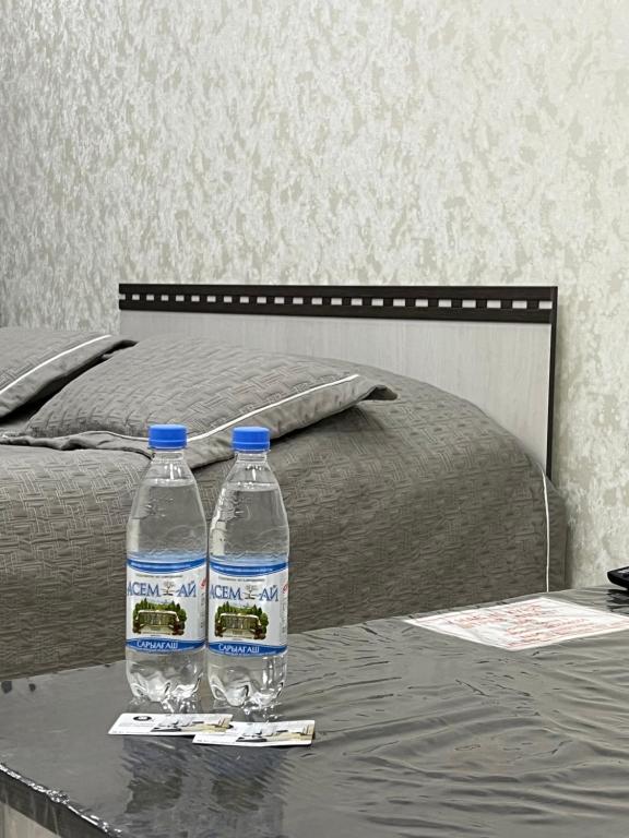 two bottles of water on a table next to a bed at Байзак- батыра 187 in Taraz