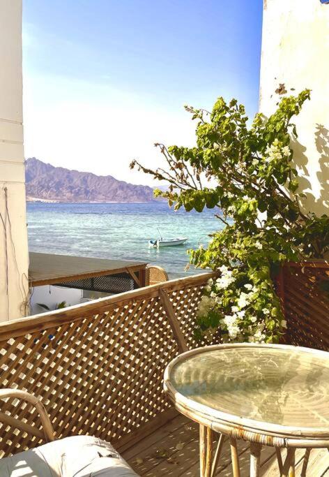 a glass table sitting on a balcony overlooking the ocean at BohemiaHouse - Duplex By the sea in Dahab