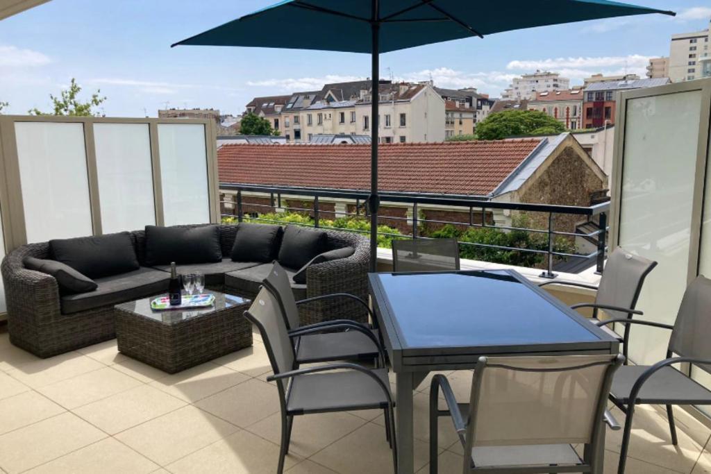 a patio with a couch and a table and an umbrella at Very nice and quiet 42 m in Suresnes with parking in Suresnes