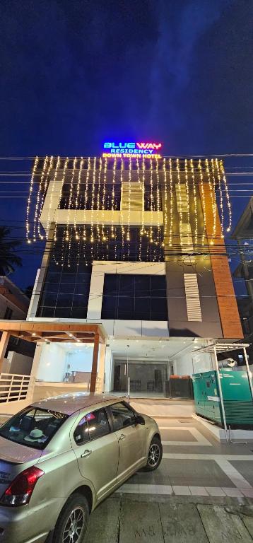 une voiture garée devant un immeuble avec des lumières dans l'établissement BLUEWAY RESIDENCY DOWNTOWN HOTEL, à Trivandrum