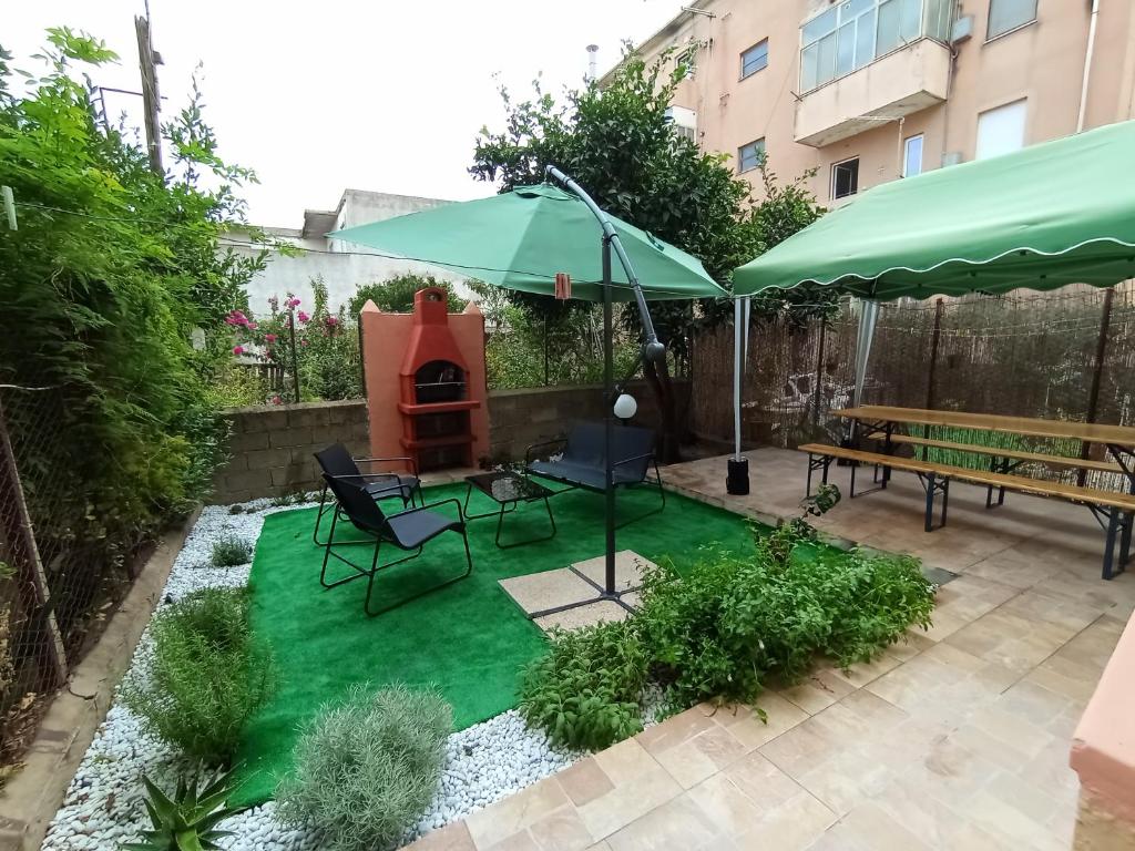 a backyard with a green lawn with a picnic table and an umbrella at Casa Clara Oristano centro con giardino in Oristano