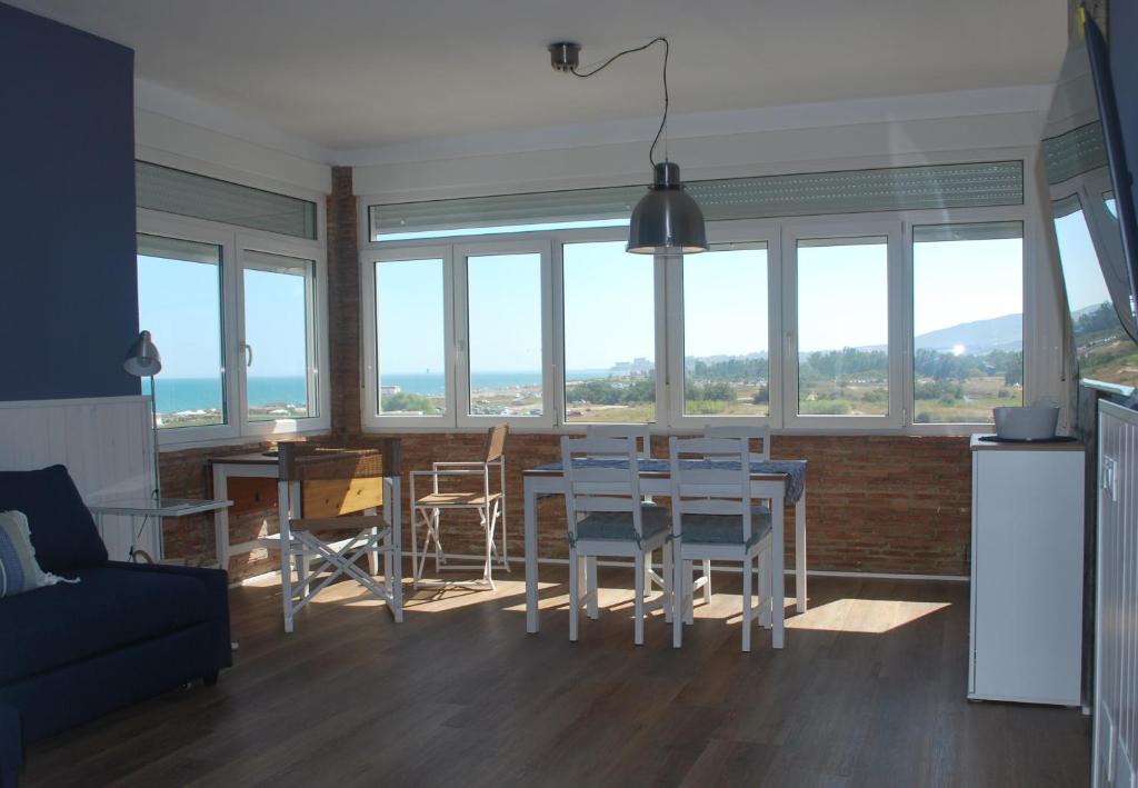 a living room with a table and chairs and windows at Una ventana al Mar en Málaga in Málaga