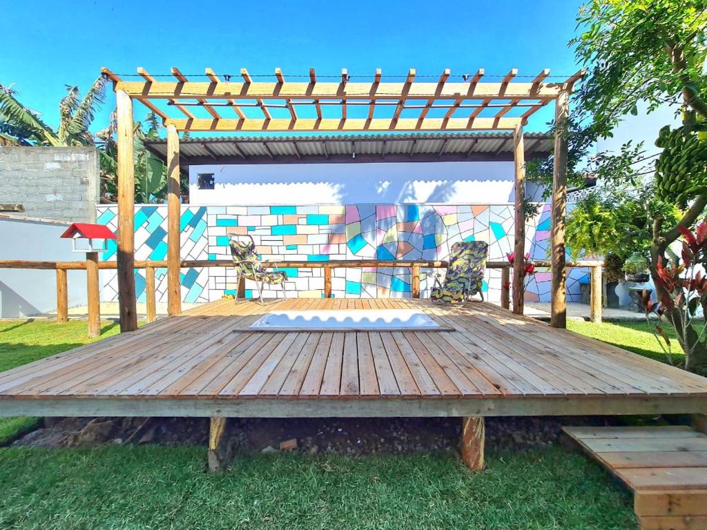 a wooden deck with a pergola and a mural at Happy Guest House in Navegantes