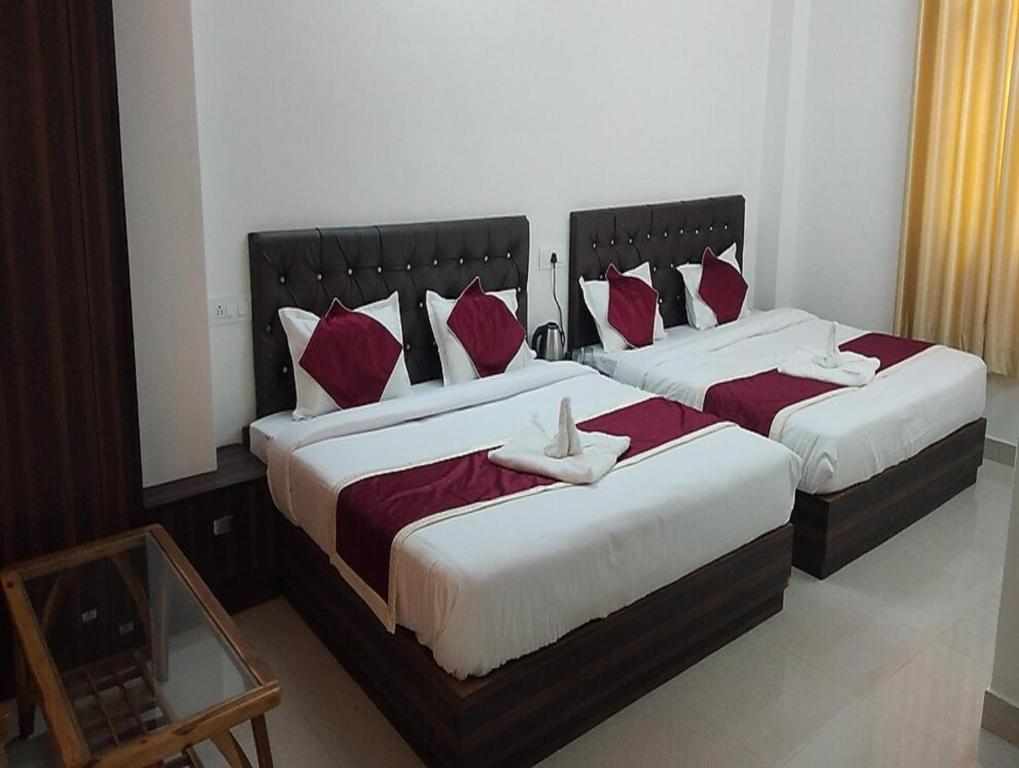two beds in a bedroom with red and white pillows at Asha Residency by StayApart in Shimla