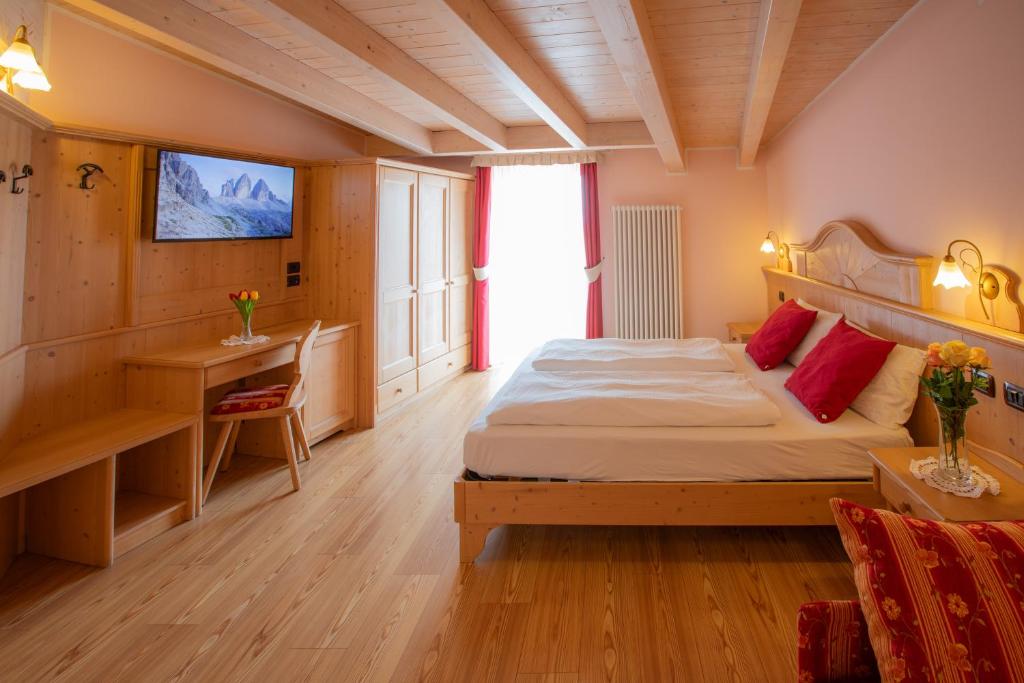Dormitorio con cama, escritorio y TV en B&B Casa Agostini, en Fai della Paganella