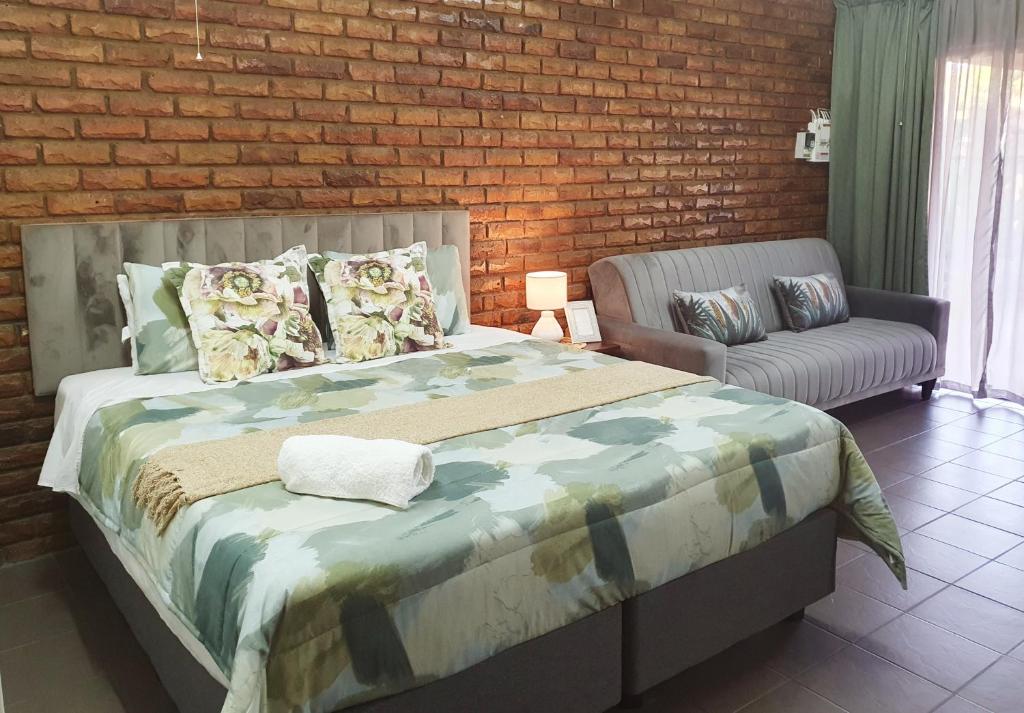 1 dormitorio con 1 cama grande y 1 sofá en Garden cottages near Savannah Mall, en Polokwane