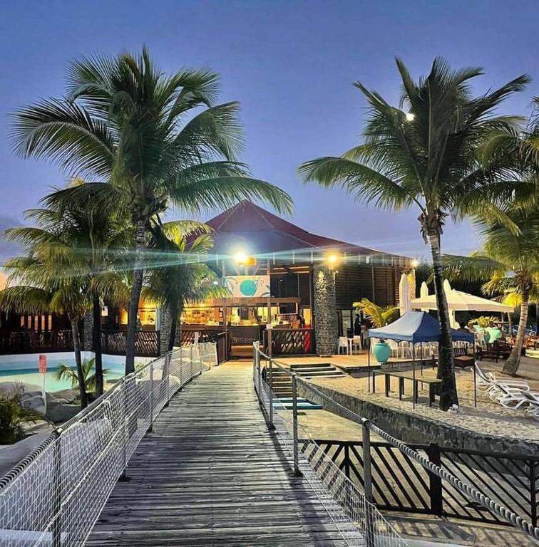 a wooden walkway leading to a resort with palm trees at Studio Climatisé avec Réservoir d'eau in Saint-François