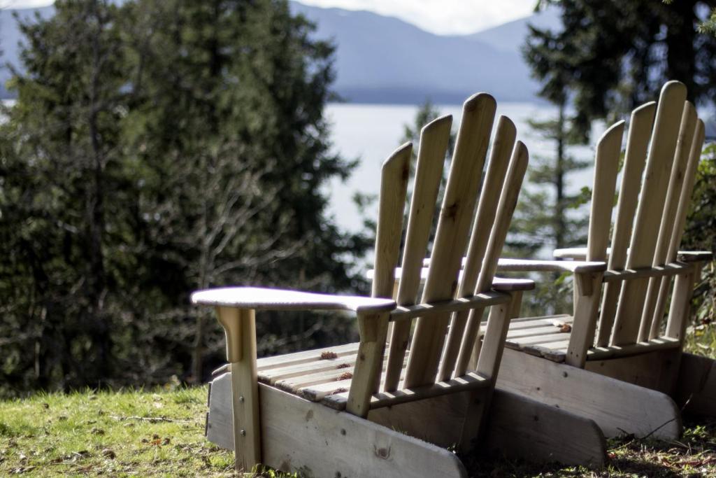 two wooden chairs sitting in the grass near the water at Quarrystone House B&B in Fernwood