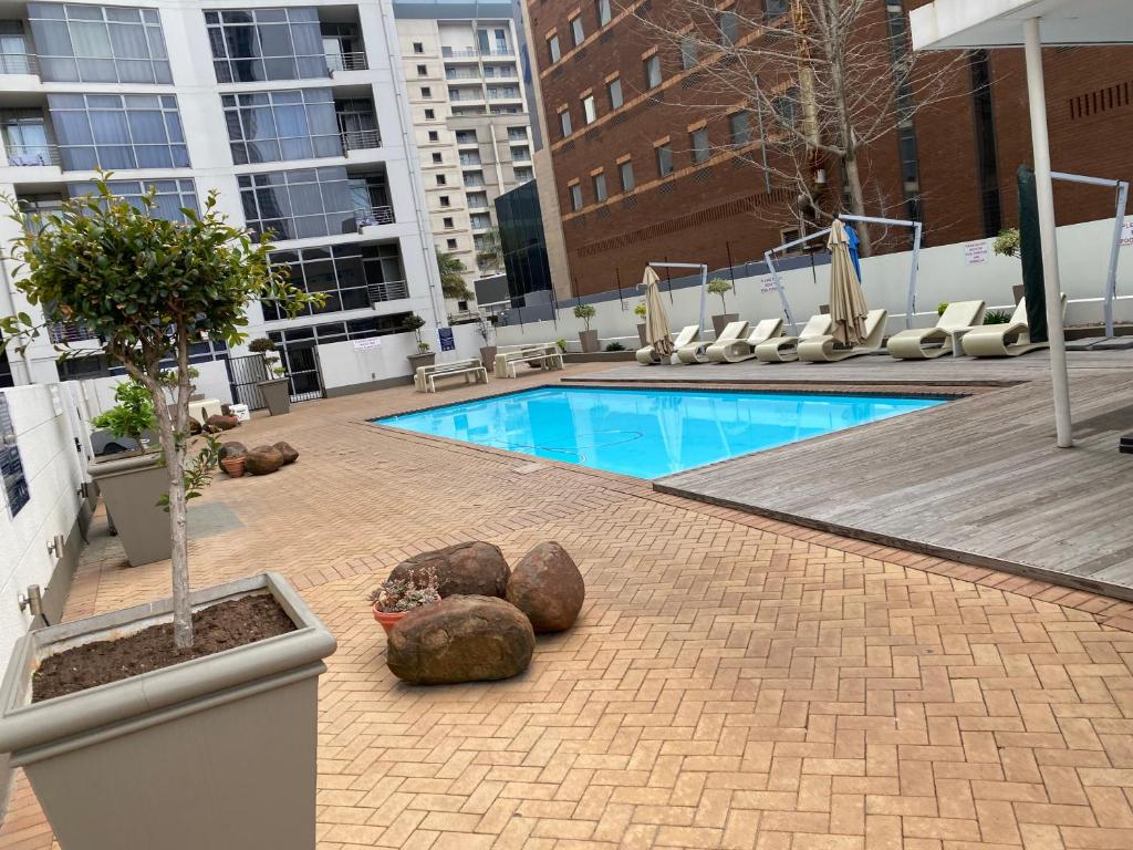 una piscina con rocas y un árbol en un edificio en Sandton Accomodation Hydro Park, en Johannesburgo