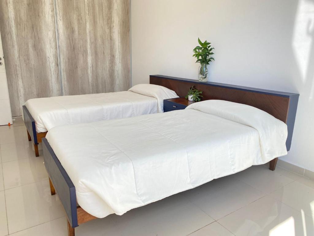 2 Betten in einem Zimmer mit weißer Bettwäsche in der Unterkunft La Palmerita in Villa Carlos Paz