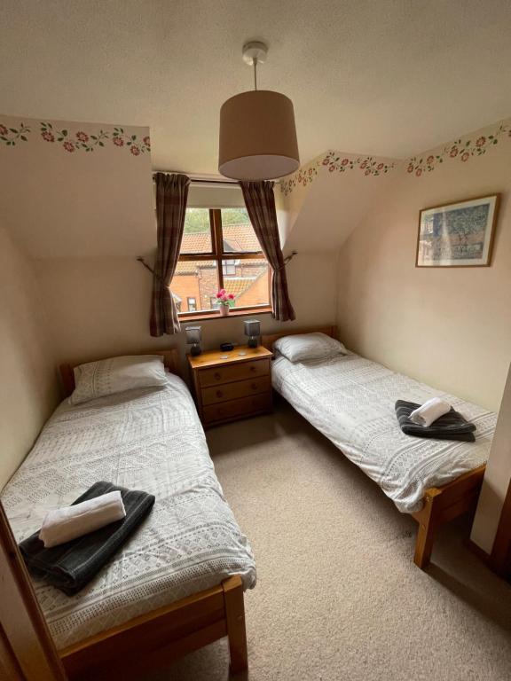 two twin beds in a room with a window at Runaway Cottage, Whitby in Whitby