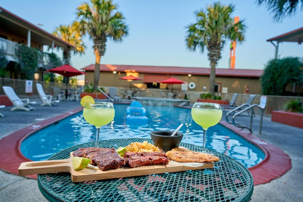 una mesa con un plato de comida y dos copas de vino en Family Garden Inn & Suites, en Laredo