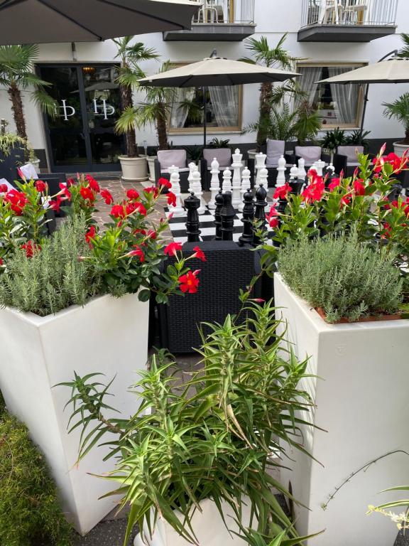 a group of flowers in white planters in front of a building at Hotel La Perla in Riva del Garda