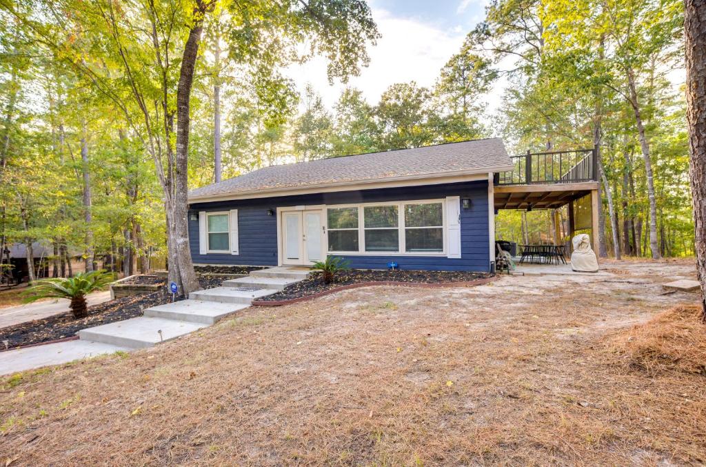 una pequeña casa azul en el bosque con un patio en Lake Livingston Cabin Half-Mi to the Water!, en Coldspring