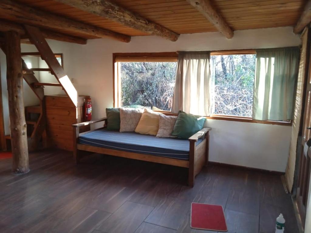 a bed in a room with two windows at Cabaña con Costa de Rio in El Hoyo