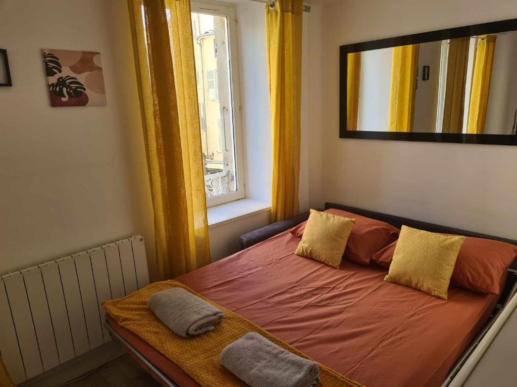 a bedroom with a bed with orange sheets and a window at Studio de la fontaine in Romans-sur-Isère
