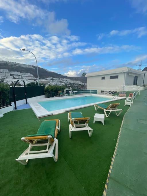 a group of lounge chairs and a swimming pool at Apartment Montaña Clara & pool in Mogán