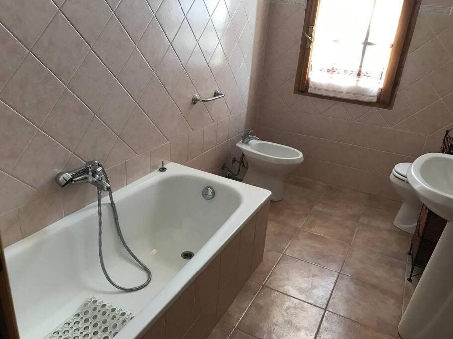 y baño con bañera, aseo y lavamanos. en Appartamento Ginepro, en Capitana
