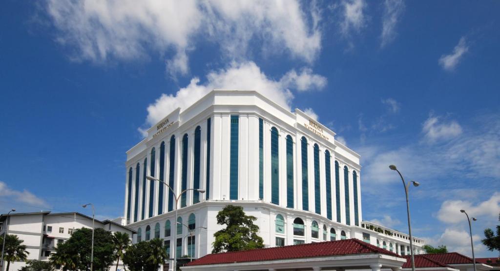 a large white building with a blue sky and clouds at Berjaya Waterfront Hotel in Johor Bahru