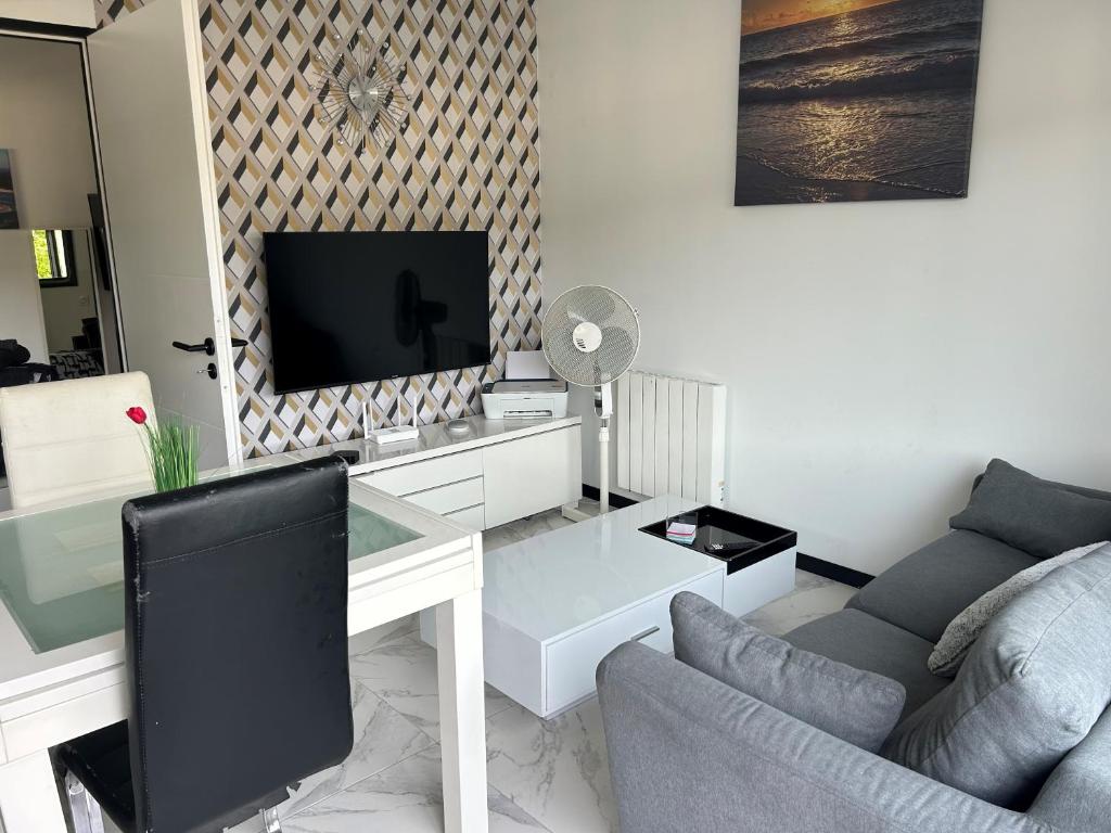 uma sala de estar com uma secretária, uma televisão e um sofá em Dépendance région bordelaise em Saint-Loubès