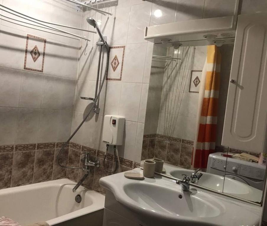 uma casa de banho com um lavatório, uma banheira e um espelho. em Makij apartment for night 5 em Narva