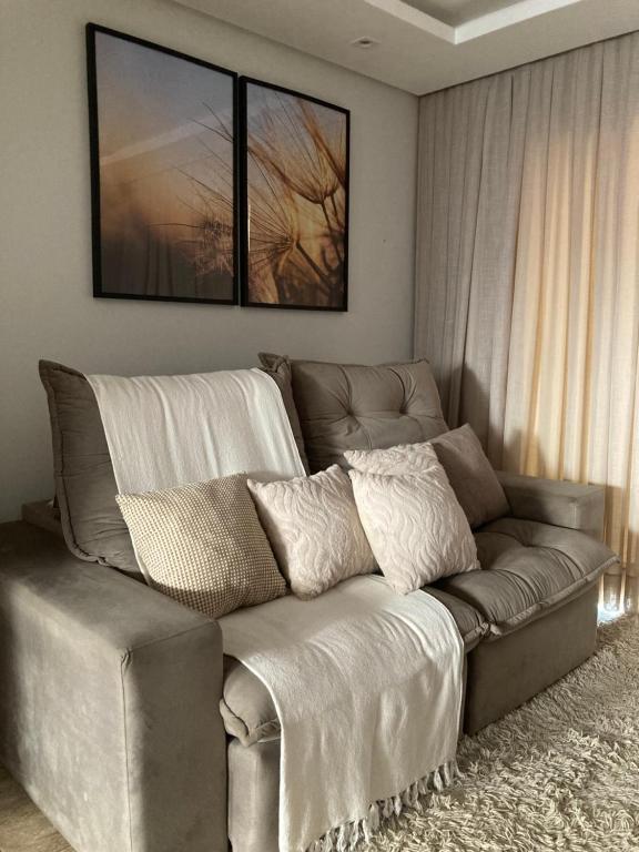 a couch in a living room with two pictures on the wall at Casa completa e confortável in Leopoldina