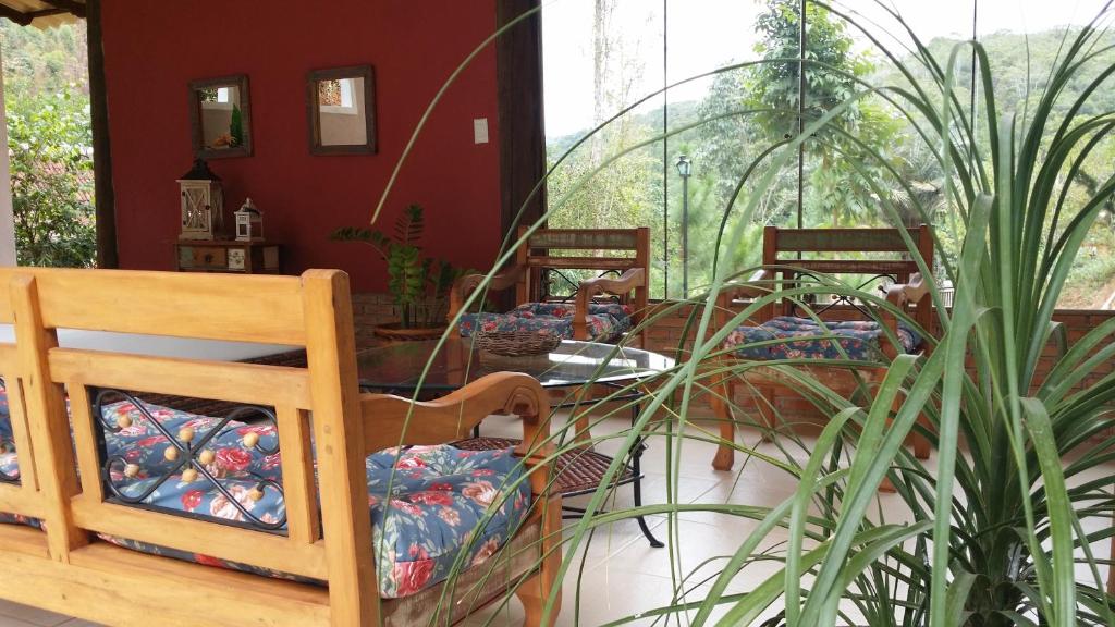 un groupe de chaises et de tables dans une pièce ornée de plantes dans l'établissement Pousada Casa Donadello, à Matilde