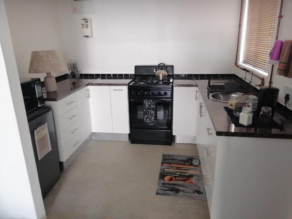 eine Küche mit einem schwarzen Herd und einer Spüle in der Unterkunft Langbeentjie Inn The Final Chapter in Kapstadt