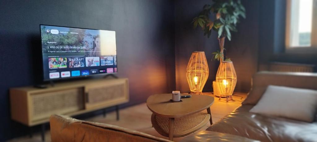 a living room with a couch and a tv and a table at Au pied du mur in Huy