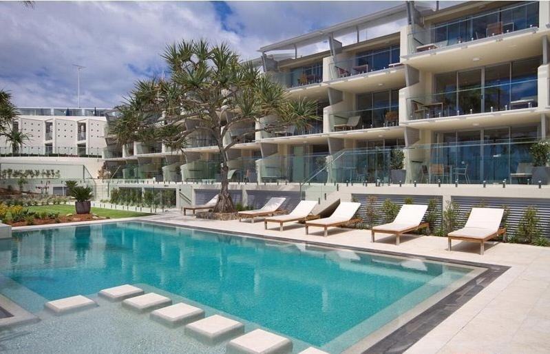 a swimming pool in front of a apartment building at Fairshore 28 Beachfront Escape in Noosa Heads