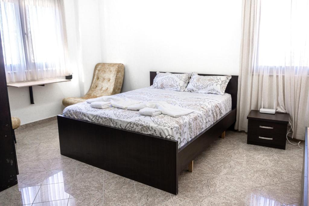 een slaapkamer met een bed met een stoel en ramen bij City Center Two Private Bedrooms near Scanderbeg Square on Shared Apartment in Tirana