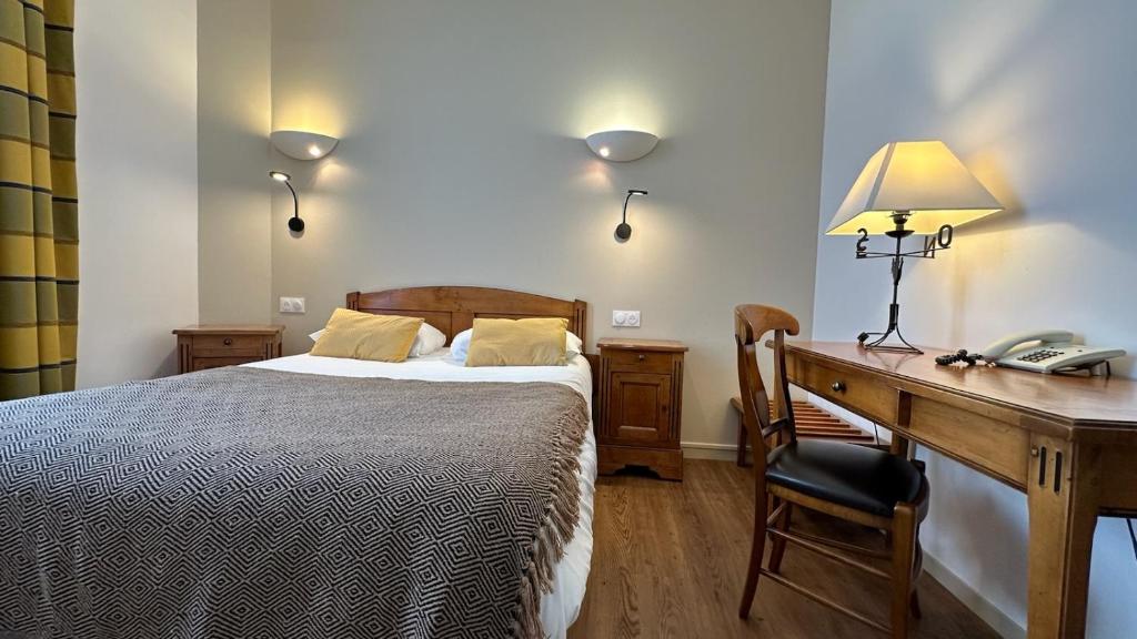 a bedroom with a bed and a desk with a telephone at Logis Hôtel de la Tête Noire in Autun