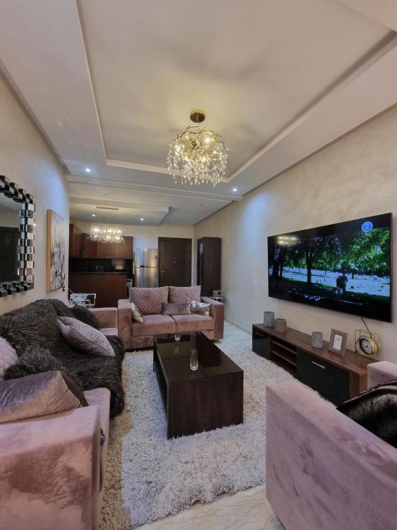 een woonkamer met een grote flatscreen-tv bij L3 avec piscine in Agadir