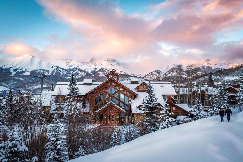 two people walking in the snow in front of a log cabin at Mountain Lodge Telluride in Telluride